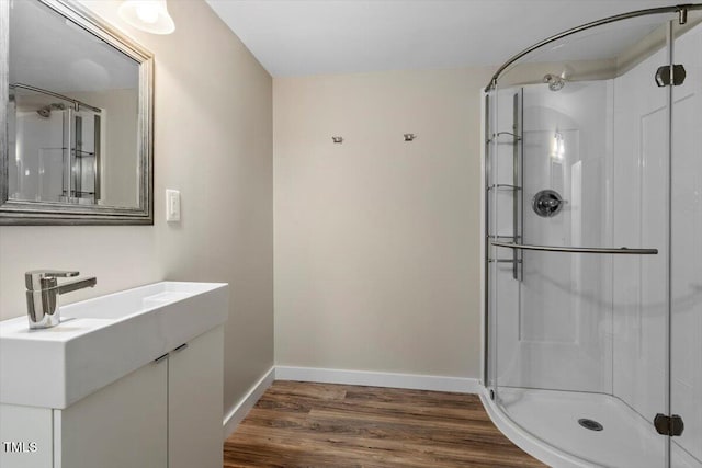 full bath with vanity, baseboards, a shower stall, and wood finished floors