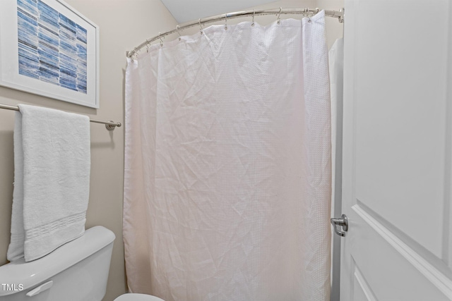 bathroom featuring toilet and curtained shower