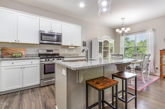 420 Cherry St, Fuquay Varina, NC 27526 - kitchen featuring dark wood-style flooring, an inviting chandelier, a sink, stainless steel appliances, and white cabinetry