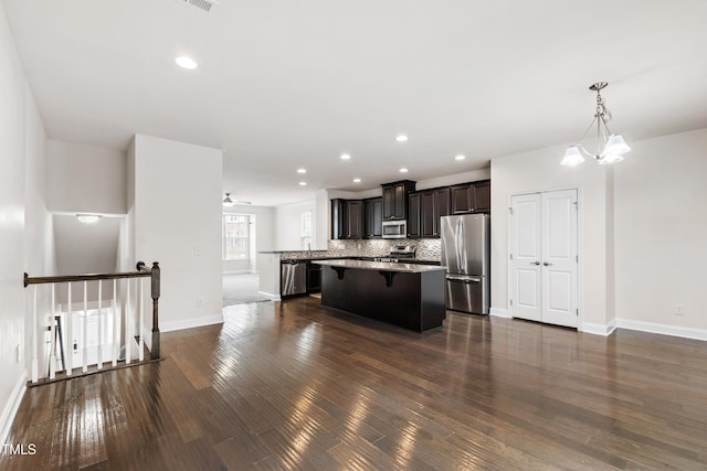 1101 Boxcar Way, Apex, NC 27502 - kitchen featuring stainless steel appliances, a breakfast bar, a kitchen island, dark wood finished floors, and baseboards