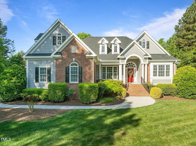 view of front of home with brick siding, a shingled roof, and a front yard