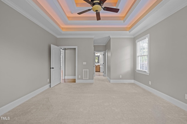 unfurnished bedroom featuring crown molding, a tray ceiling, light colored carpet, and visible vents