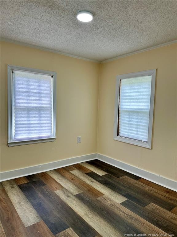 spare room featuring dark wood-style floors, a wealth of natural light, a textured ceiling, and crown molding