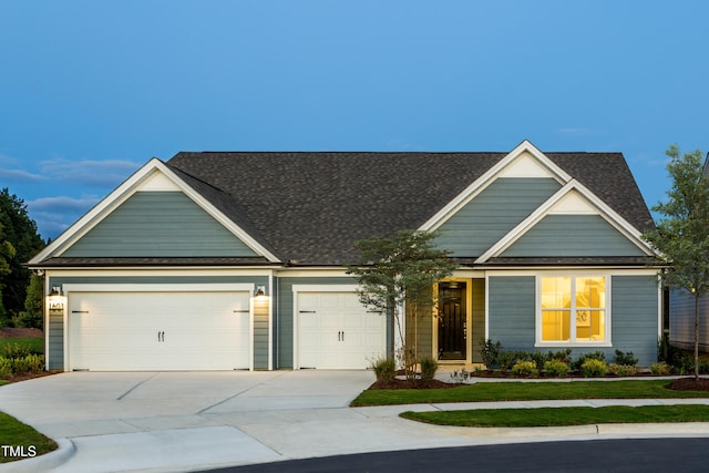 view of front of property featuring roof with shingles, concrete driveway, and an attached garage