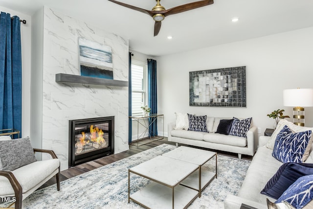 living area featuring ceiling fan, a premium fireplace, baseboards, recessed lighting, and wood finished floors