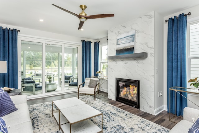 living room with a premium fireplace, baseboards, recessed lighting, wood finished floors, and a ceiling fan