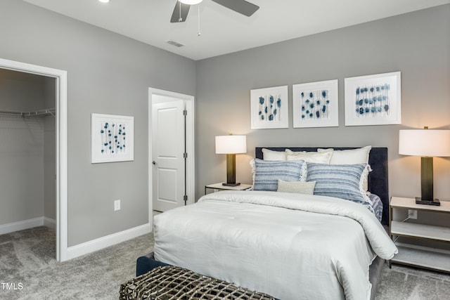 carpeted bedroom with a closet, a ceiling fan, a walk in closet, visible vents, and baseboards