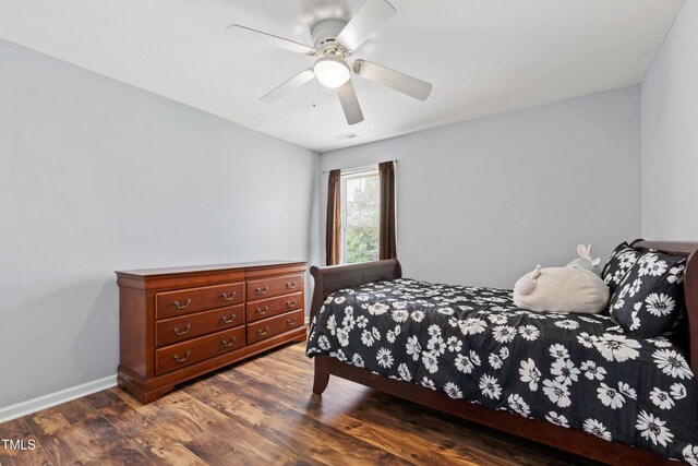 bedroom with dark wood-type flooring, a ceiling fan, and baseboards
