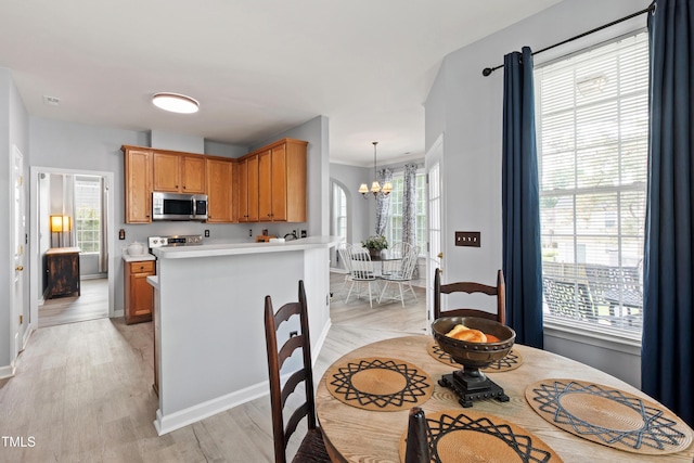dining area featuring a chandelier, light wood-type flooring, and baseboards