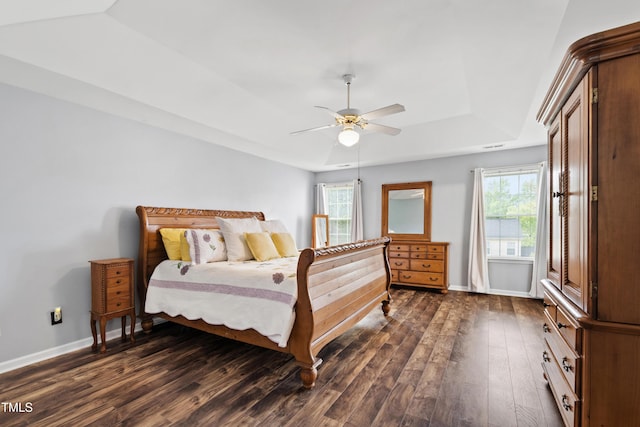 bedroom with dark wood-style floors, a raised ceiling, baseboards, and ceiling fan