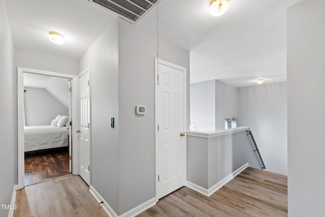 hall featuring an upstairs landing, wood finished floors, and baseboards