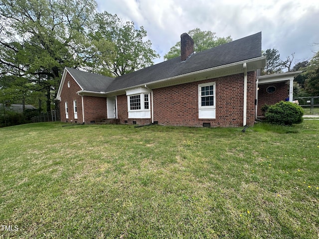 rear view of property with a lawn, fence, a chimney, and brick siding