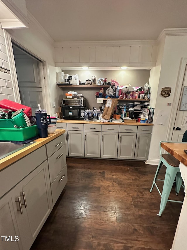 kitchen featuring dark wood finished floors, ornamental molding, and butcher block counters