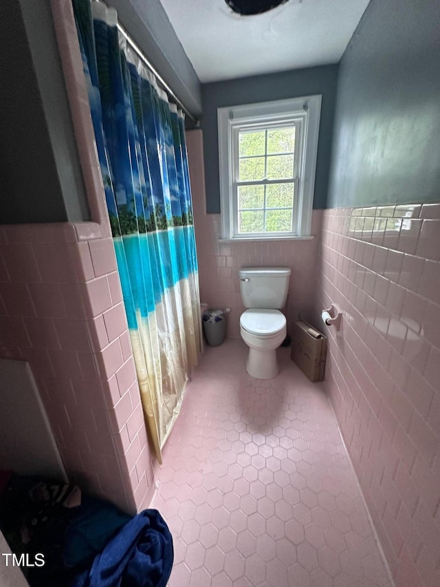 full bath with tile patterned flooring, toilet, a wainscoted wall, tile walls, and curtained shower