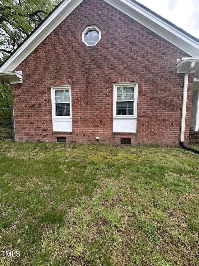 view of side of home with a yard, brick siding, and crawl space