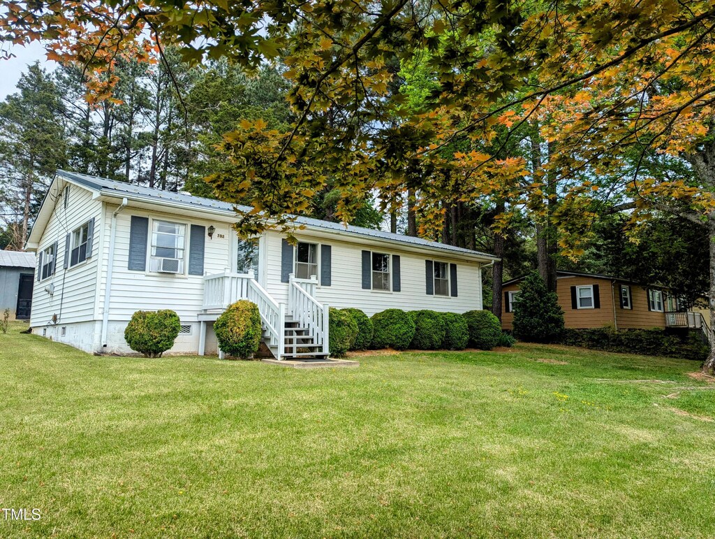 view of front of home with cooling unit, a front yard, metal roof, and crawl space
