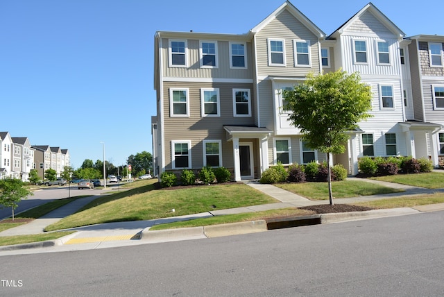 view of property featuring board and batten siding, a residential view, and a front lawn