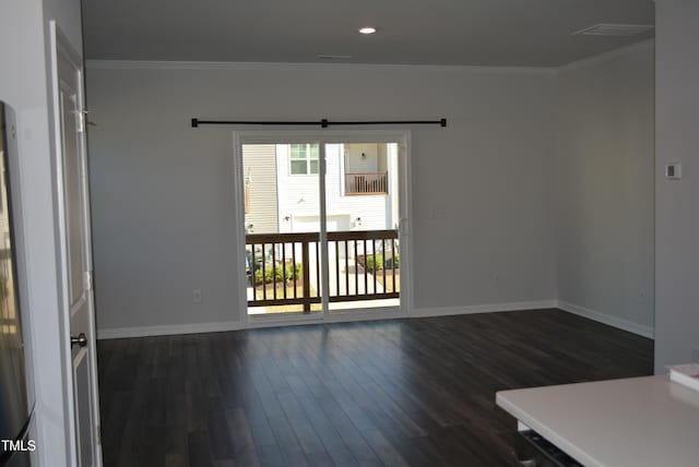 spare room featuring crown molding, dark wood finished floors, and baseboards