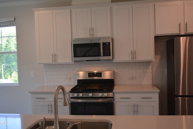 kitchen featuring light countertops, decorative backsplash, stainless steel appliances, and a sink