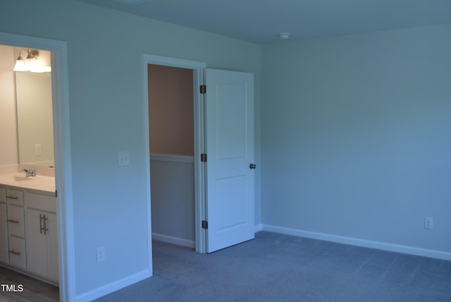 unfurnished bedroom with baseboards, a sink, carpet, and ensuite bathroom
