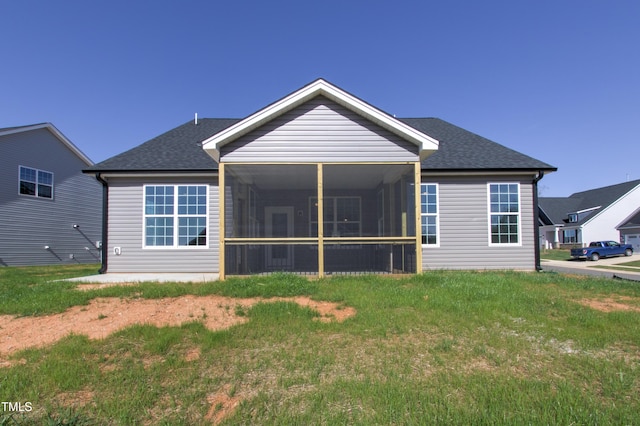 back of house with a yard, a shingled roof, and a sunroom