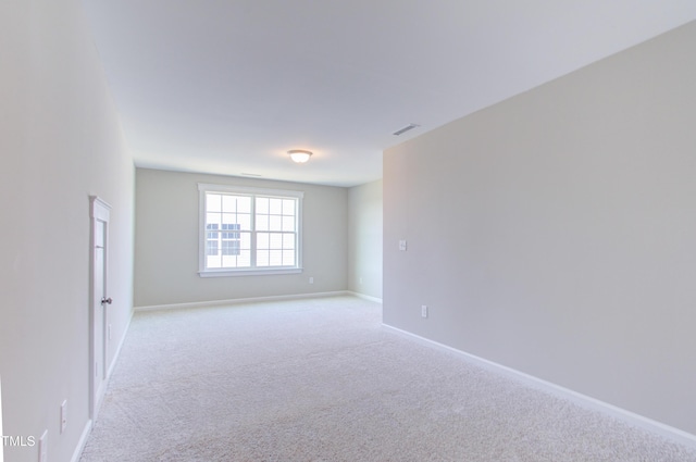 spare room featuring visible vents, light carpet, and baseboards