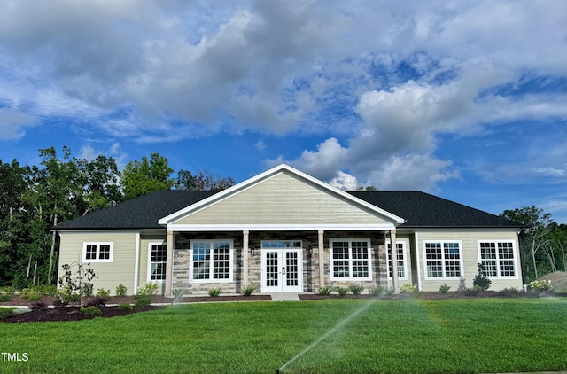view of front of house with french doors, a front yard, and stone siding