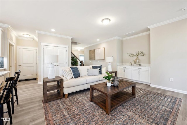 living area featuring baseboards, recessed lighting, ornamental molding, and light wood-style floors