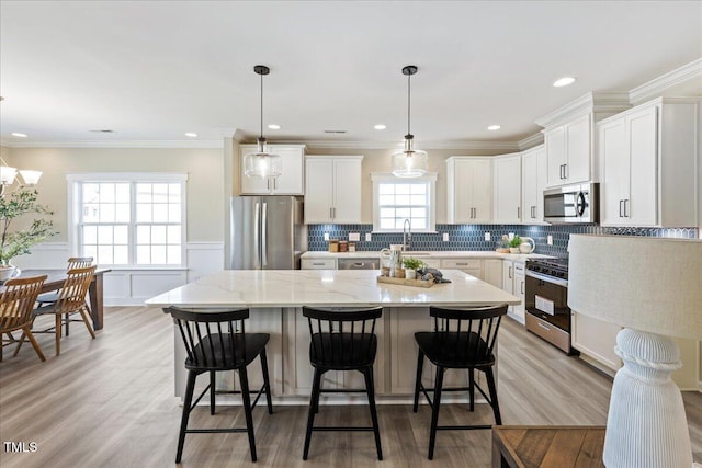 kitchen featuring a kitchen breakfast bar, white cabinets, appliances with stainless steel finishes, and a kitchen island
