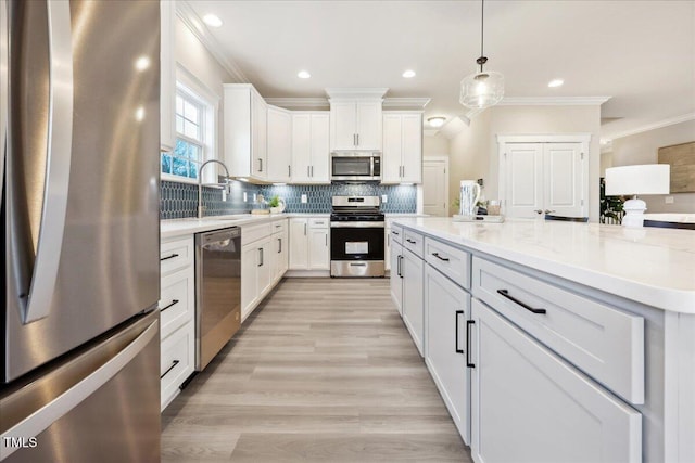 kitchen with white cabinetry, crown molding, a sink, appliances with stainless steel finishes, and backsplash