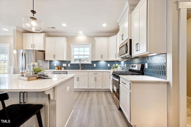 kitchen with light wood-style flooring, stainless steel appliances, white cabinetry, and crown molding
