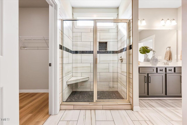 bathroom with a spacious closet, a stall shower, wood finished floors, and vanity