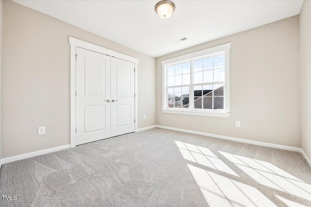 unfurnished bedroom featuring visible vents, carpet floors, and baseboards