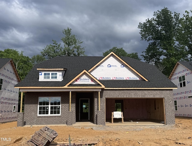 property in mid-construction with a garage, brick siding, dirt driveway, and a shingled roof
