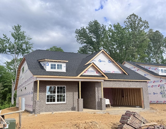 property in mid-construction featuring driveway, a garage, a shingled roof, and brick siding