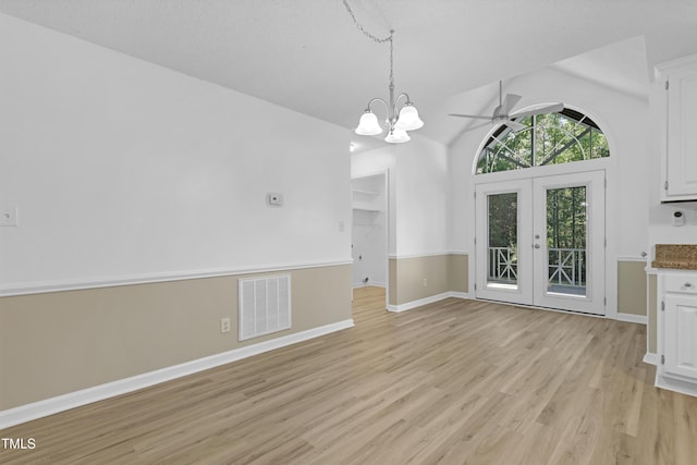 unfurnished dining area with visible vents, vaulted ceiling, baseboards, ceiling fan with notable chandelier, and light wood finished floors