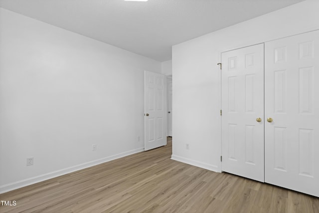 unfurnished bedroom with baseboards, a closet, and light wood finished floors