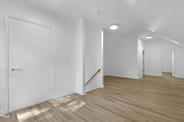 additional living space featuring baseboards, light wood-type flooring, and lofted ceiling