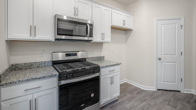 412 Ember St, Sanford, NC 27330 - kitchen with light stone countertops, light wood-style floors, baseboards, white cabinetry, and appliances with stainless steel finishes