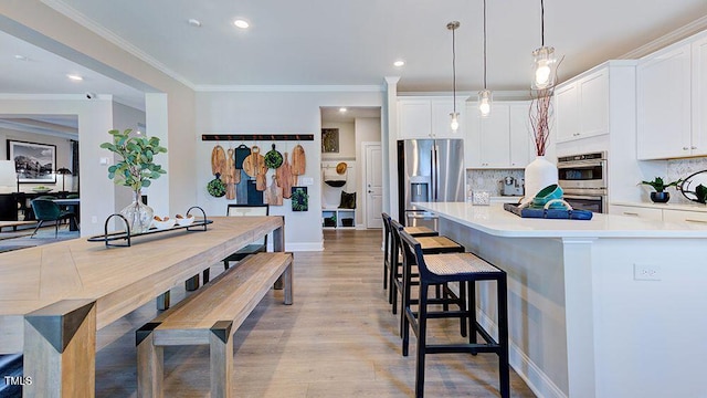 2625 Stonington Dr, Cary, NC 27523 - kitchen with backsplash, white cabinetry, appliances with stainless steel finishes, and a kitchen bar
