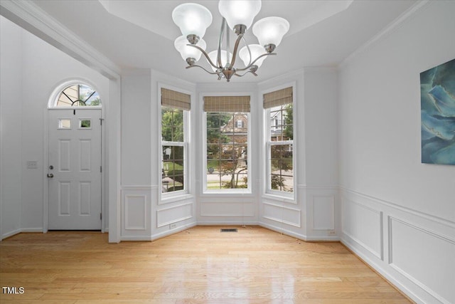 1012 Delta River Way, Knightdale, NC 27545 - unfurnished dining area with a chandelier, light wood-style flooring, ornamental molding, a decorative wall, and a wainscoted wall