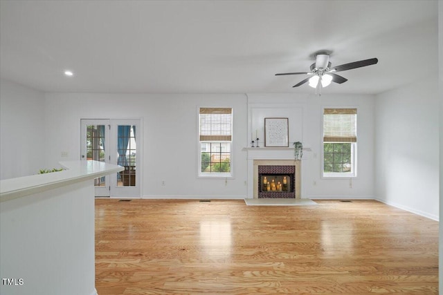 1012 Delta River Way, Knightdale, NC 27545 - unfurnished living room with a lit fireplace, light wood-style flooring, a ceiling fan, baseboards, and recessed lighting