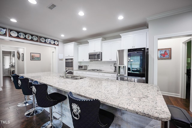 1013 Chelsea Run Ln, Apex, NC 27502 - kitchen featuring appliances with stainless steel finishes, a sink, a large island, white cabinets, and crown molding