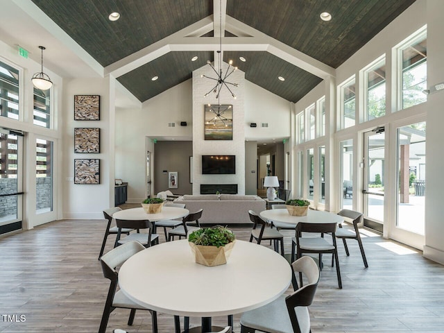 dining space with high vaulted ceiling, recessed lighting, wood finished floors, and a wealth of natural light