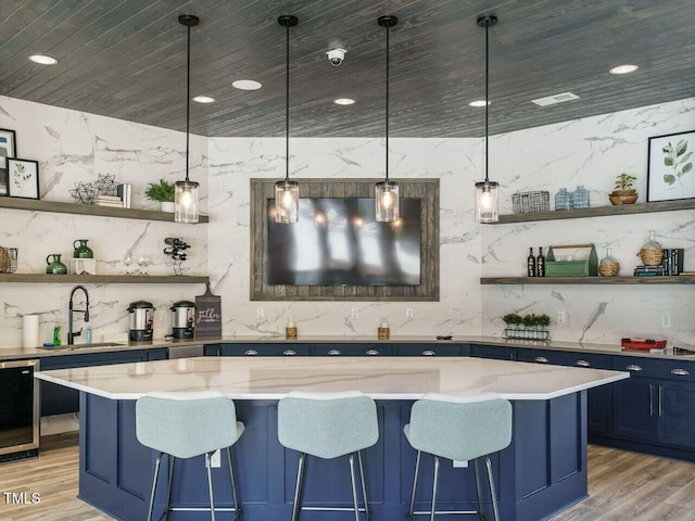 bar featuring a sink, wooden ceiling, hanging light fixtures, and light wood finished floors