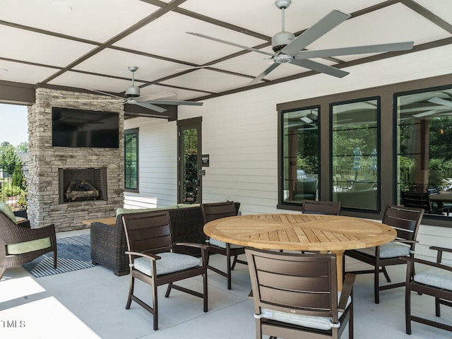 view of patio / terrace featuring an outdoor stone fireplace, outdoor dining area, and ceiling fan