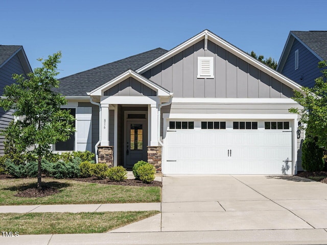 craftsman-style house with stone siding, roof with shingles, board and batten siding, concrete driveway, and an attached garage