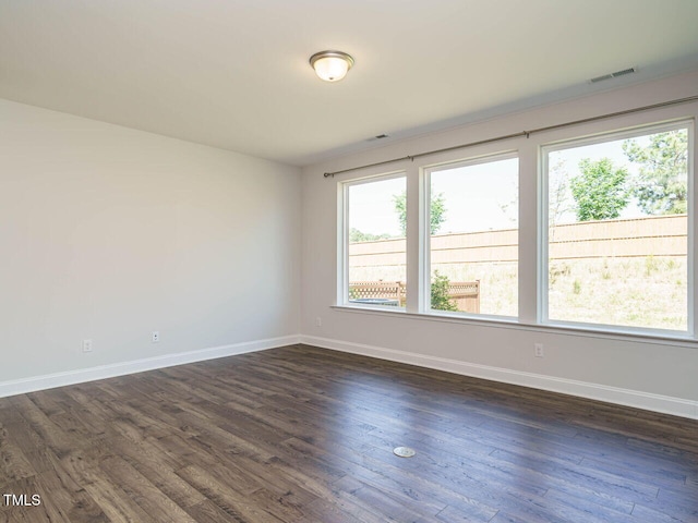 spare room with visible vents, baseboards, dark wood-type flooring, and a healthy amount of sunlight