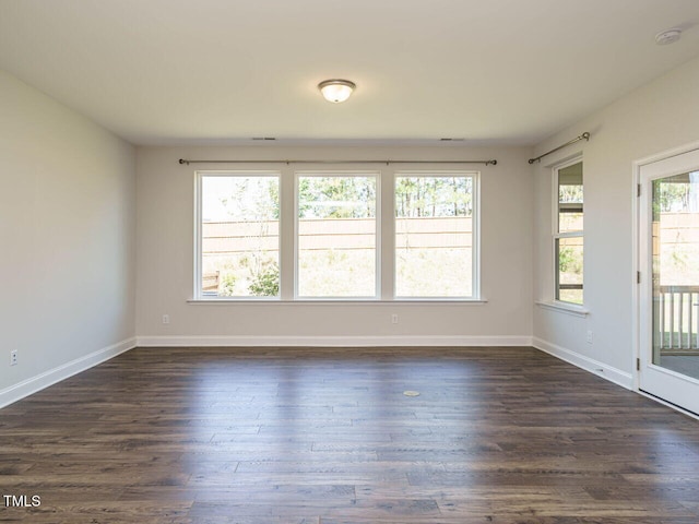 spare room featuring baseboards and dark wood finished floors