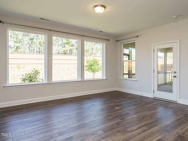 unfurnished room with dark wood-type flooring, baseboards, and visible vents